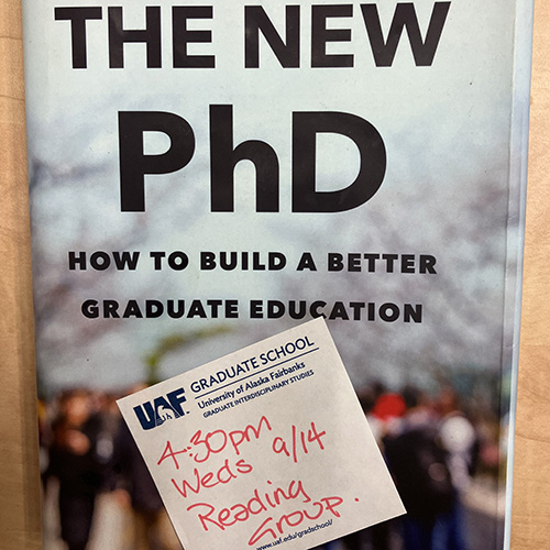 Photo of book cover of "The New PhD" with a UAF Graduate School sticky note that has the date and time of the reading group on it