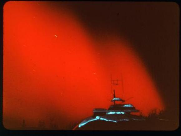 A red shade covers a portion of the night sky above a building with antennas.