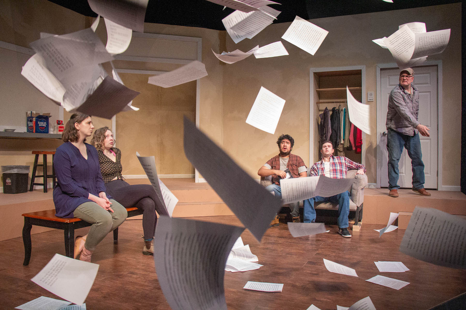 People sit in a room while papers fall around them