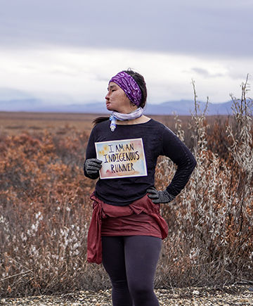 woman holding a sign that reads I am an indigenous runner
