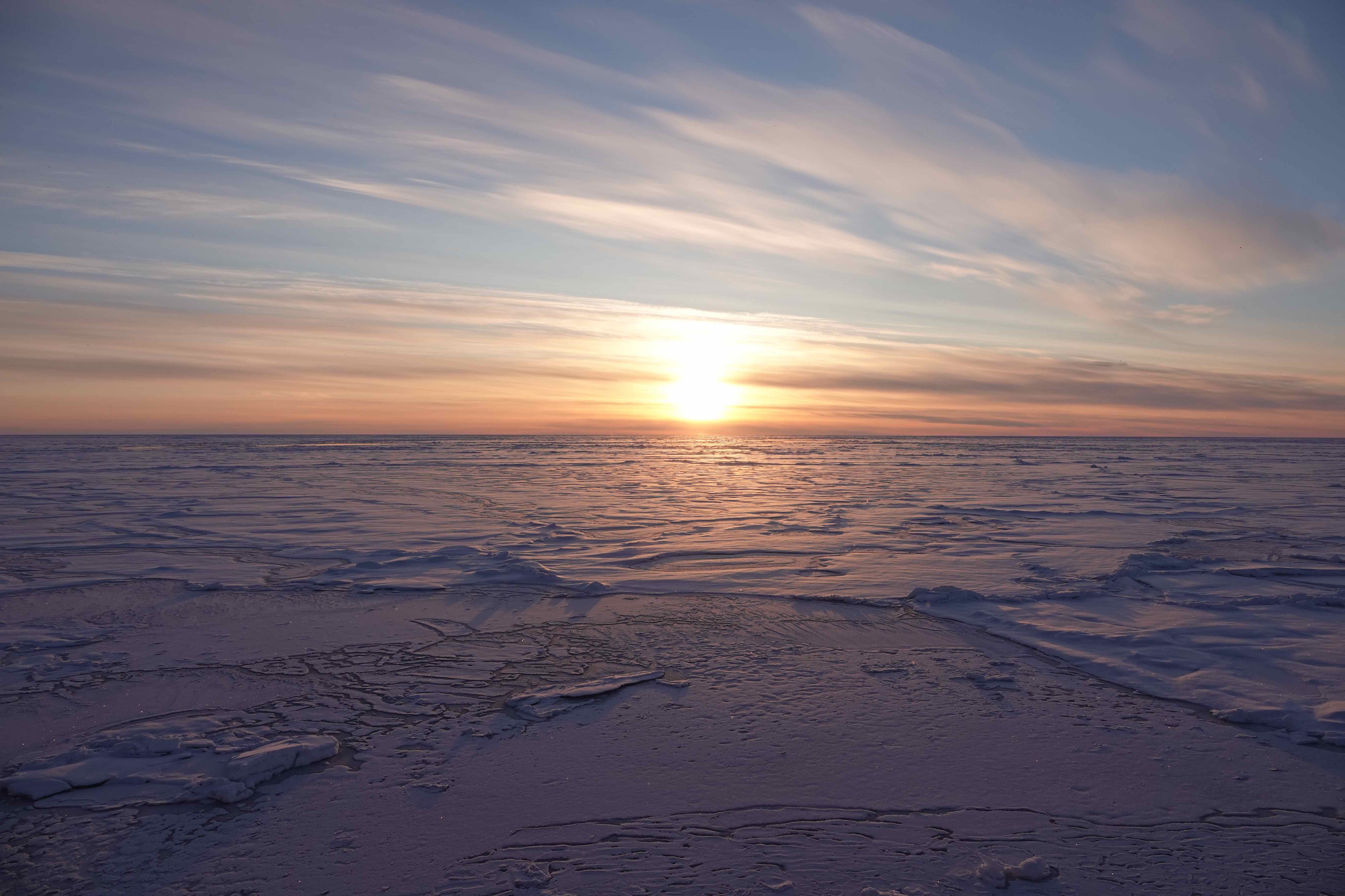 Sun reflects on the snow-covered Arctic sea ice, which has a variety of surface types.