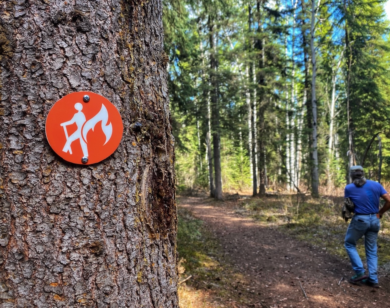 A trail marker with a wildfire symbol on it. 