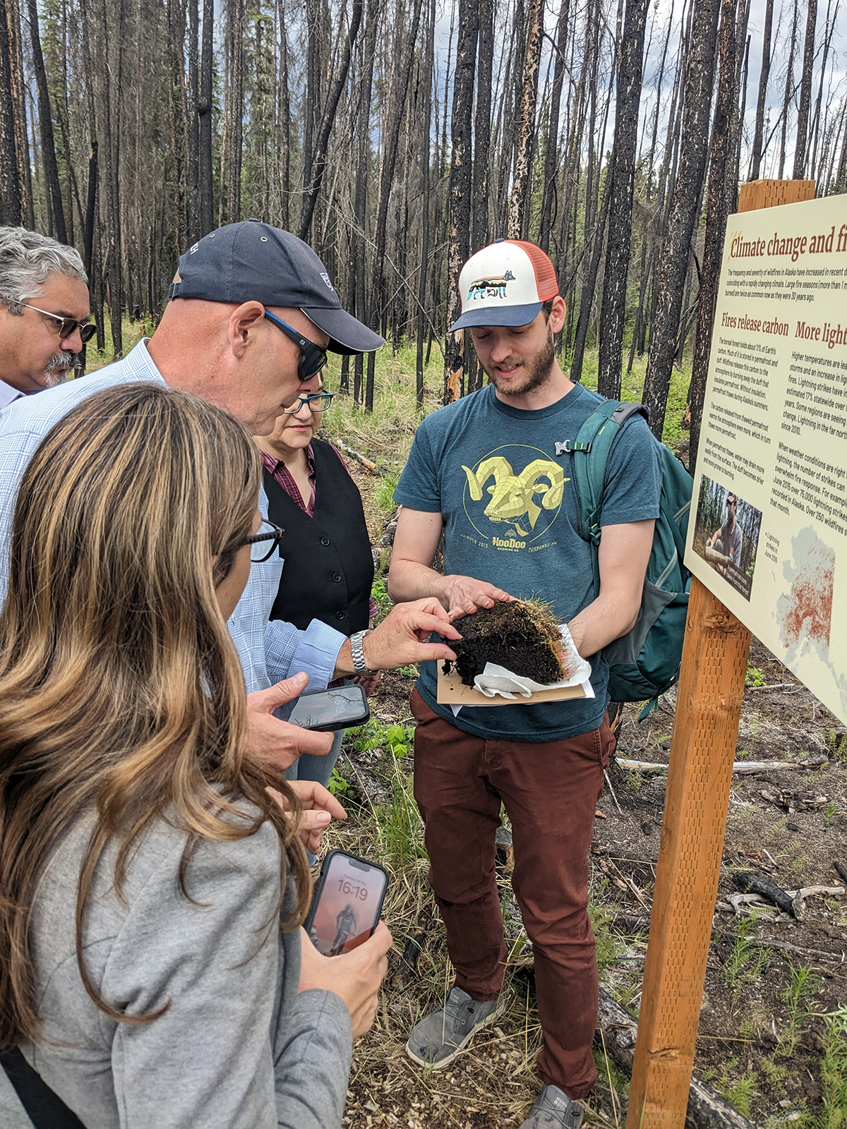 People look at a soil sample at an interpretive trail. 