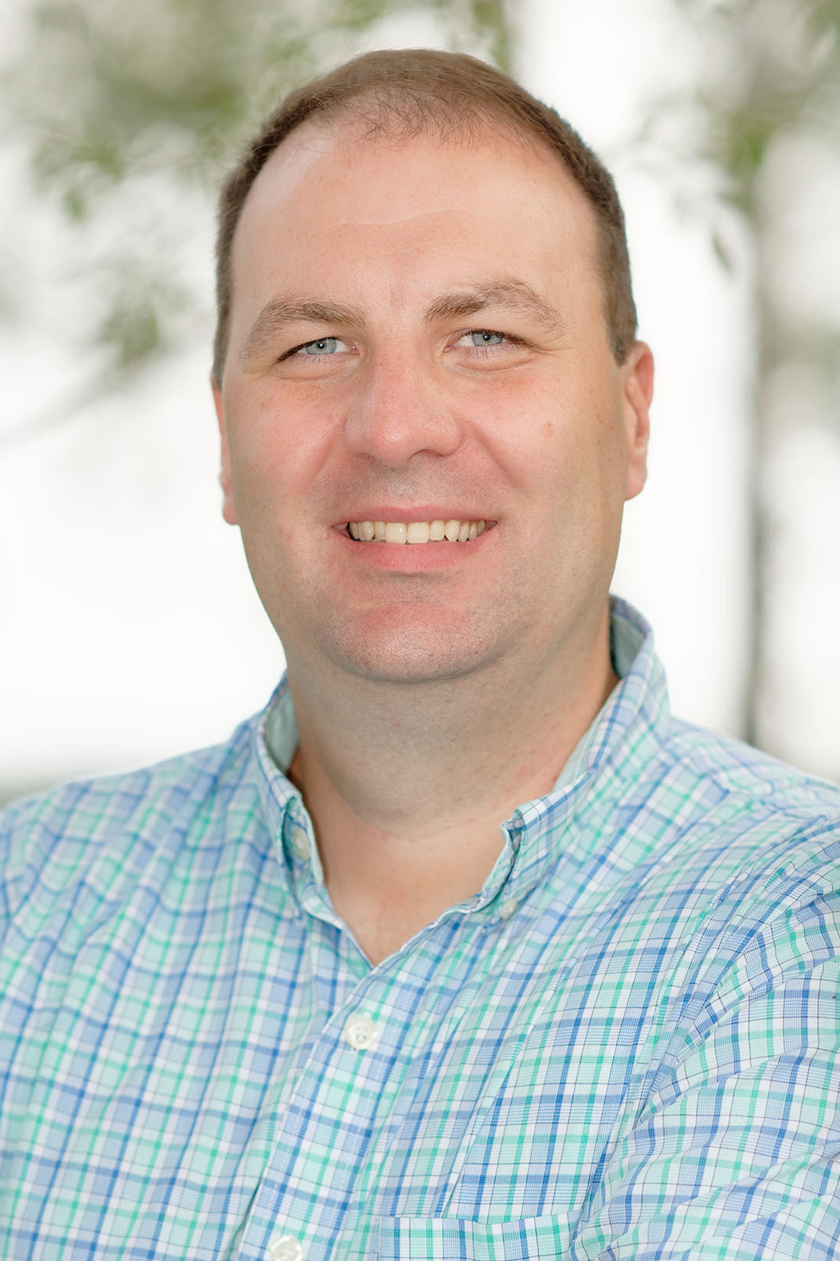 a portrait of a smiling man in a plaid shirt