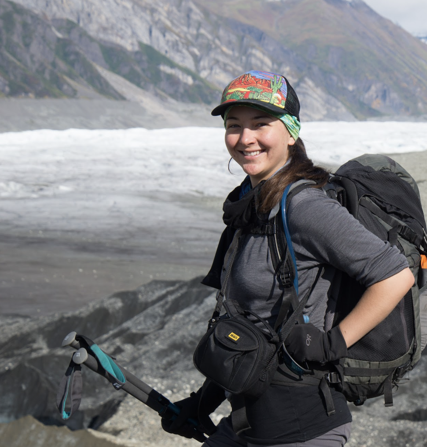 a smiling woman standing with mountains and a glacier in the background