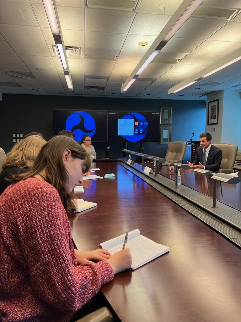 Students listen and take notes as they meet with U.S. Transportation Secretary Pete Buttigieg as part of a course focusing on energy, policy, and climate communication.