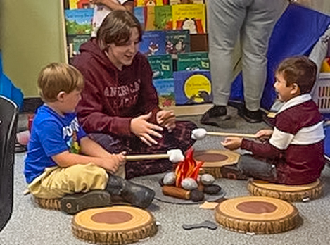Preschoolers sit around a mock campfire in their classroom under the guidance of Early Childhood Education teachers.