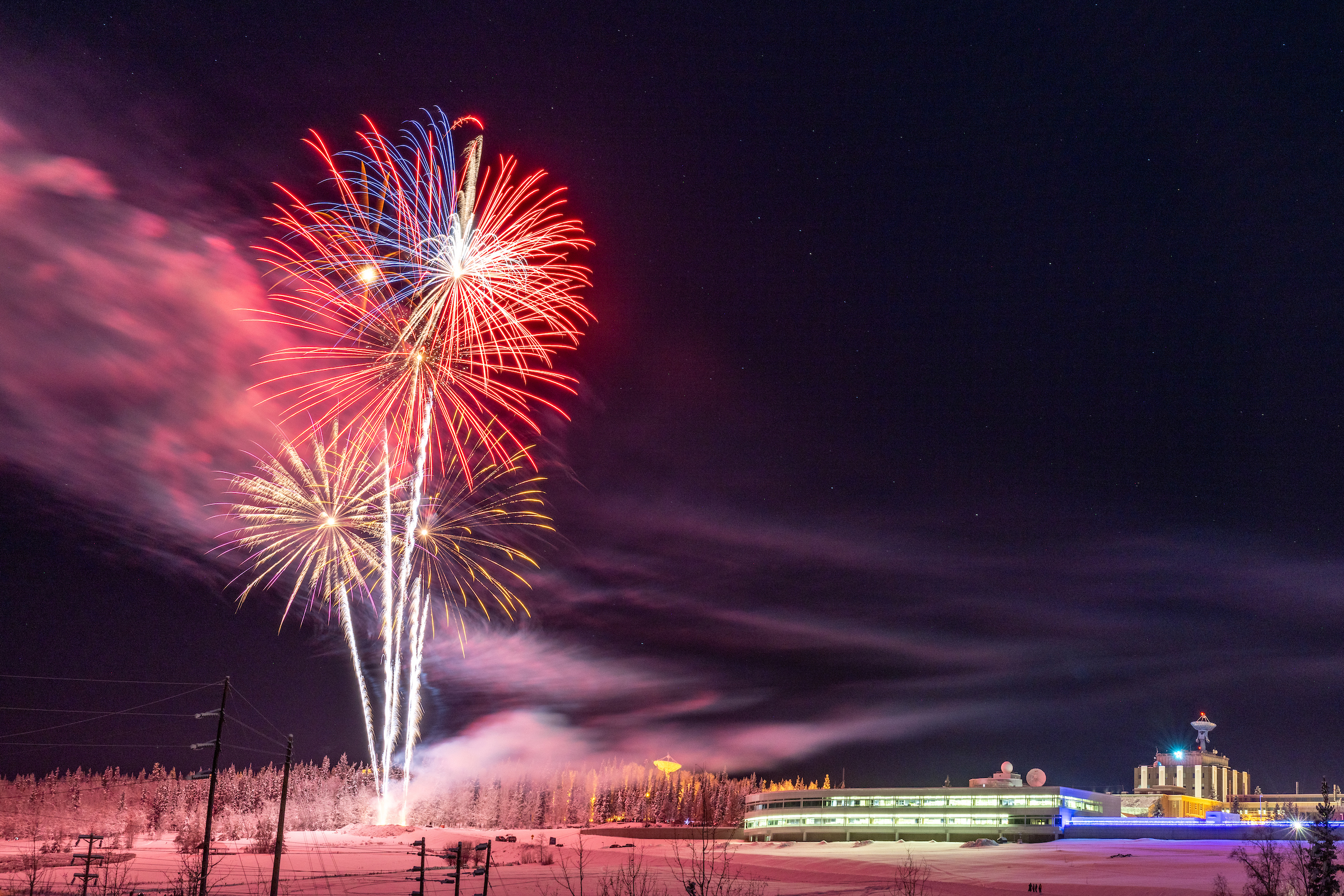 fireworks against a dark sky with buildings 