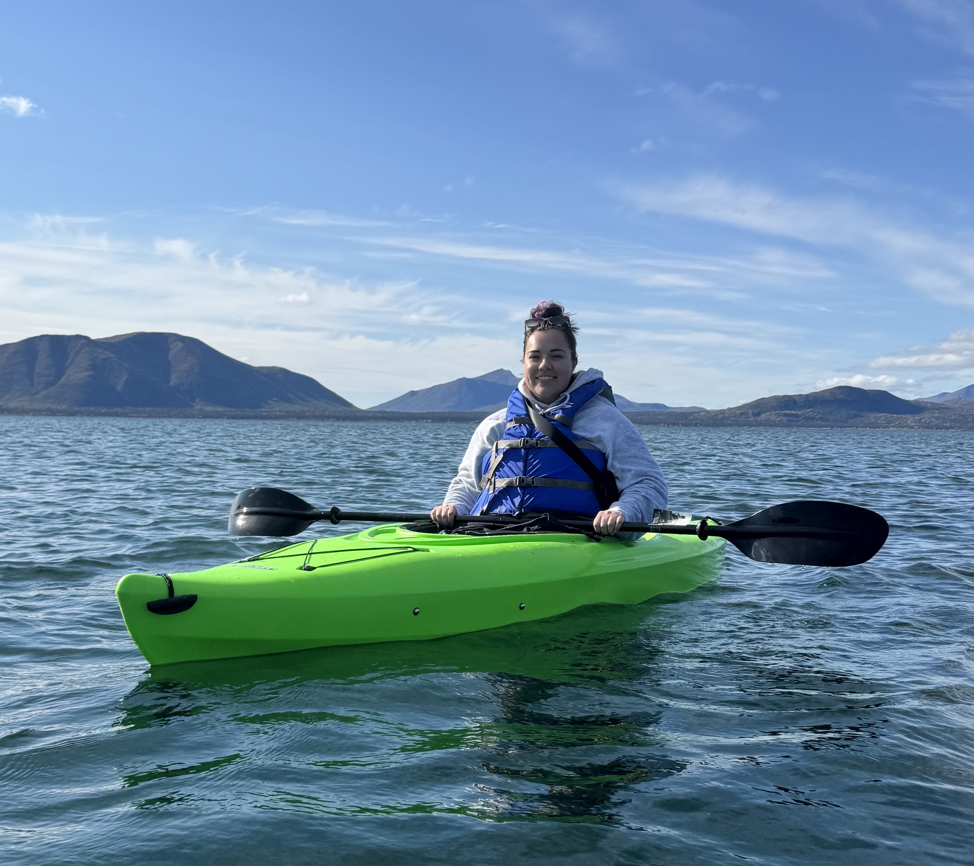 A woman on the water aboard a bright green kayak.