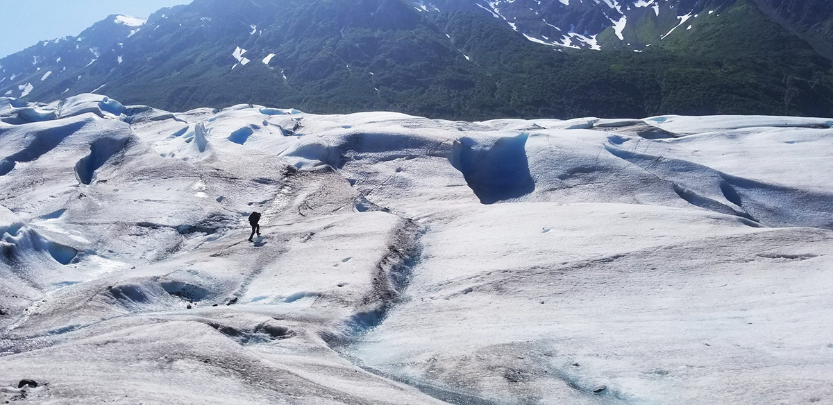 A small human figure traversing a vast glacier
