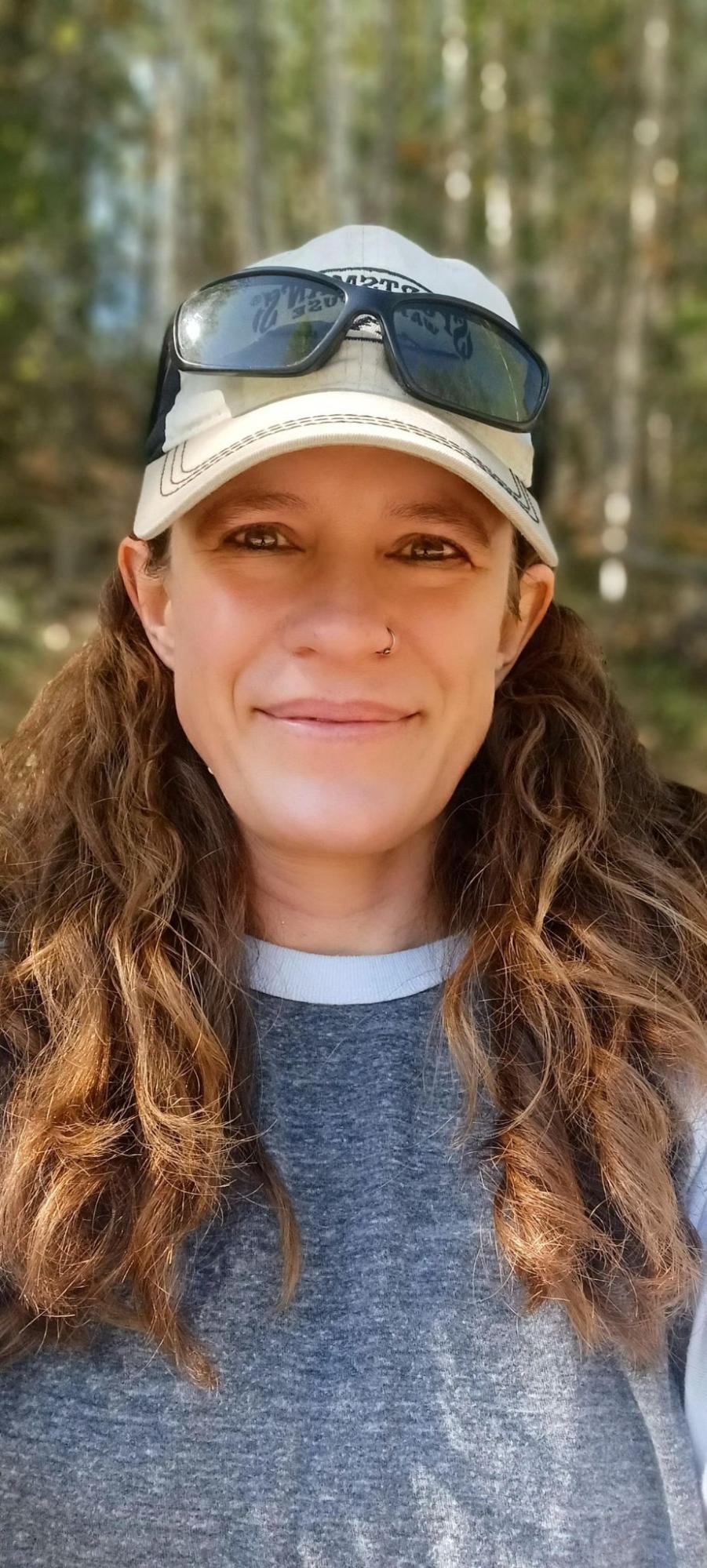 a woman with curly hair wearing a hat