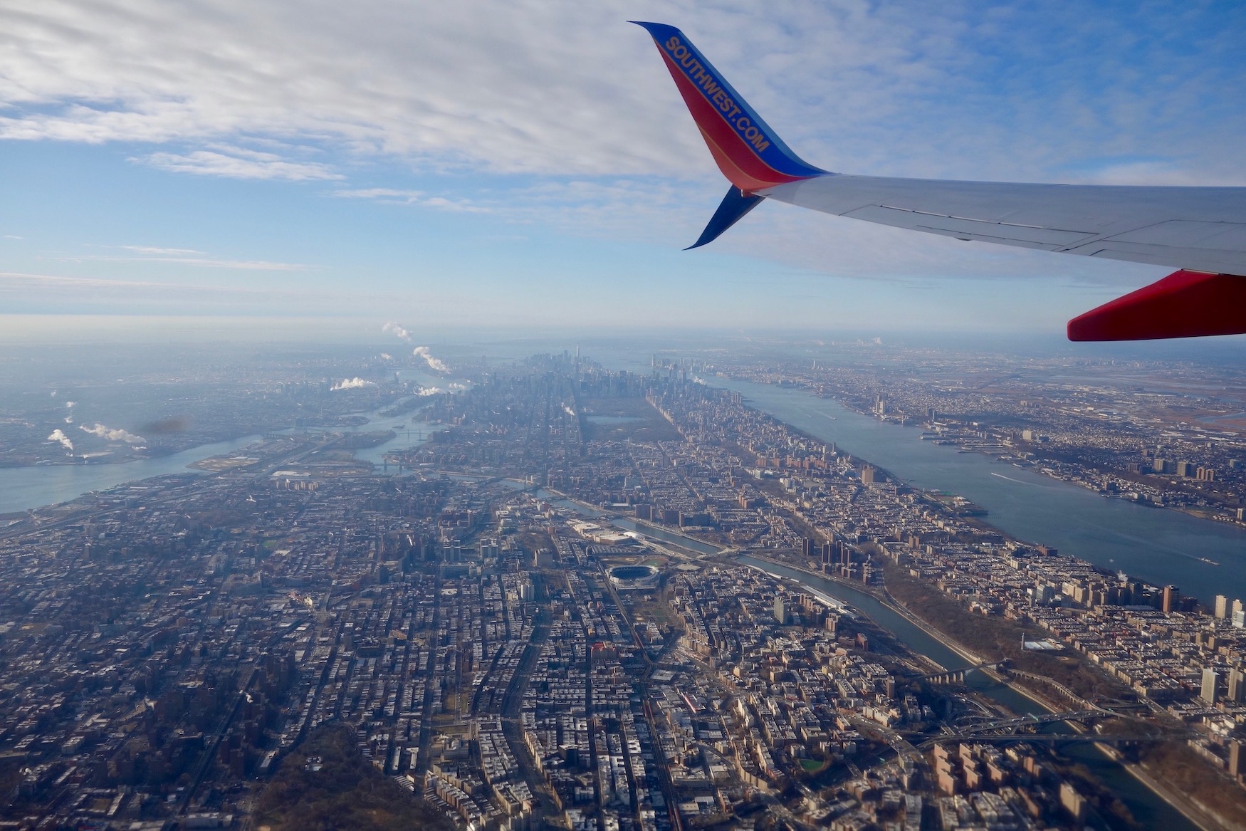 On a mostly clear day, New York City and the Hudson, Harlem and East rivers are visible below the outer wing of a Southwest Airlines 737-700 jet flying out of John F. Kennedy International Airport.
