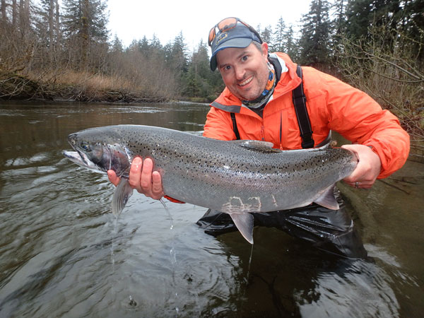 Peter Westley holds a salmon briefly just above the water of a river in Alaska.