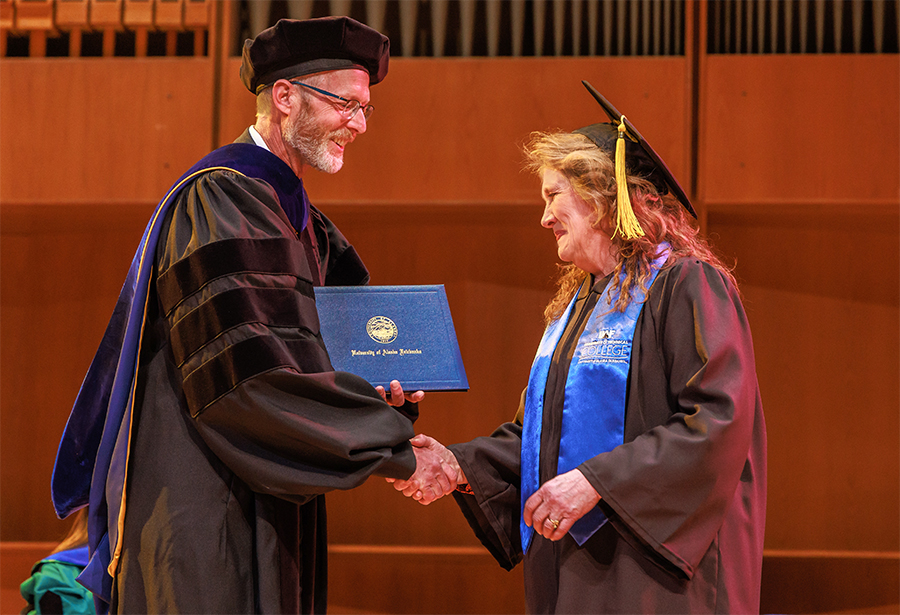 UAF Chancellor Dan White bestows emeritus status to Michele Stalder, dean of the Community and Technical College, during UAF's 101st commencement ceremonies May 5 in the Davis Concert Hall.
