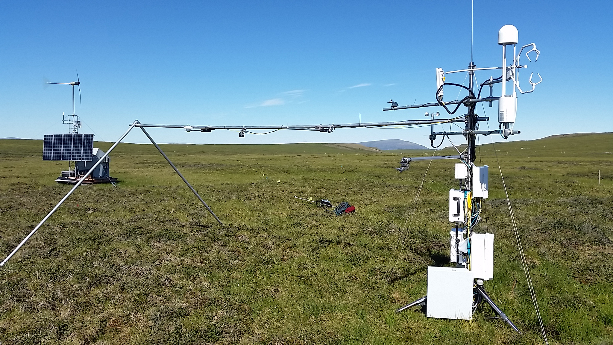 two scientific instruments stand on green tundra and grass