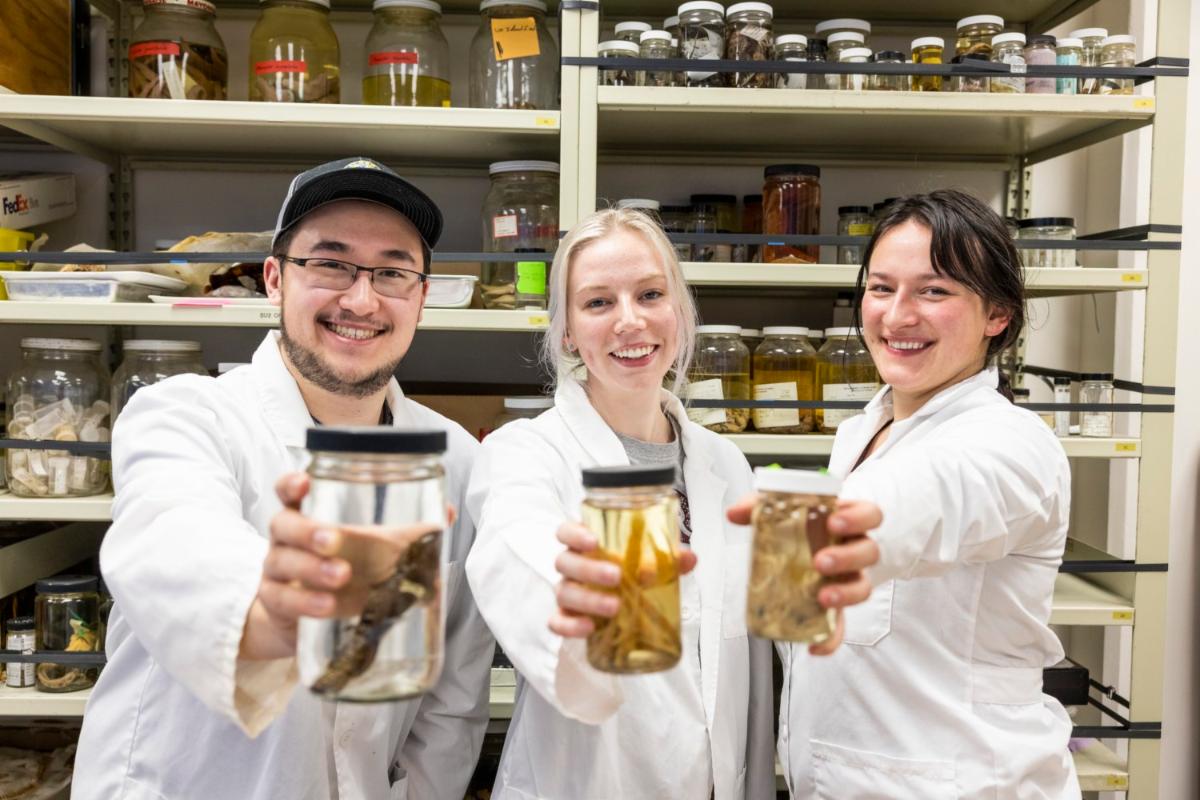 Trio of students hold up jars filled with preserved items