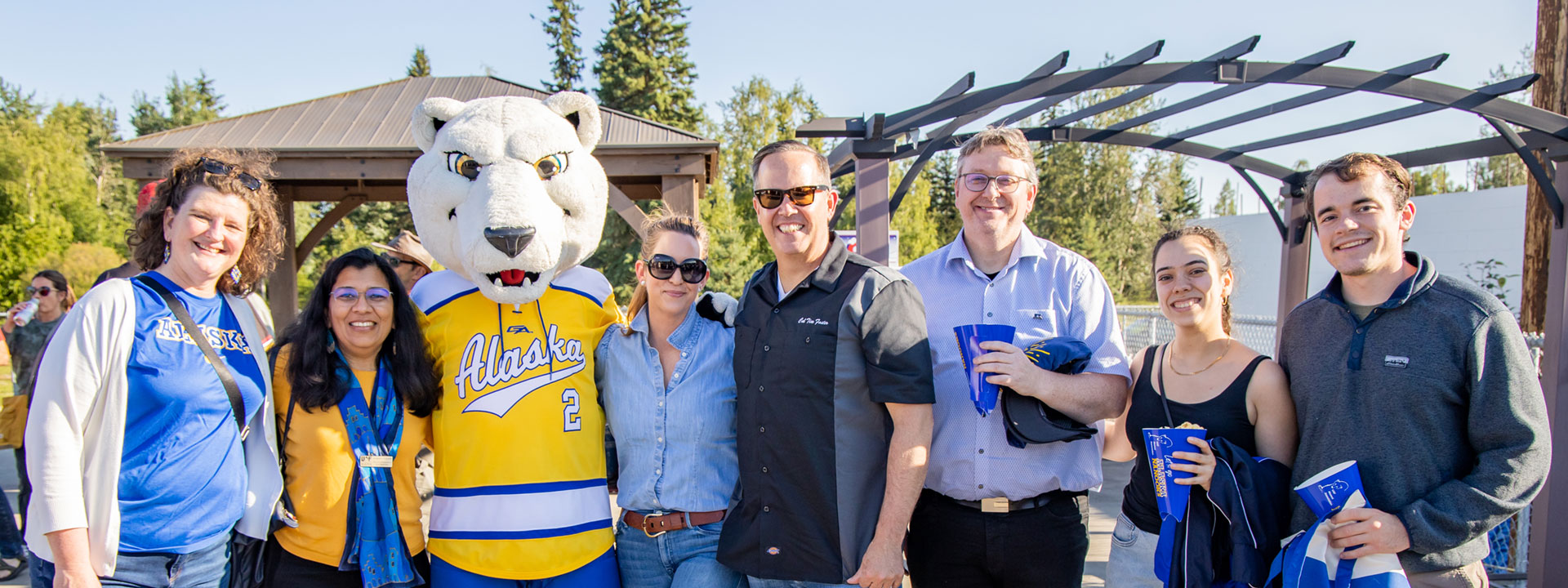 Anupma Prakash poses with a group of people and the Nanook mascot at the Georgeson Botanical Garden during the annual Alumni Nanook Rendezvous