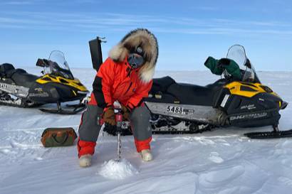 A permafrost geomorphologist from the Institute of Northern Engineering (INE), drills into the Arctic tundra to collect permafrost and hydrology data