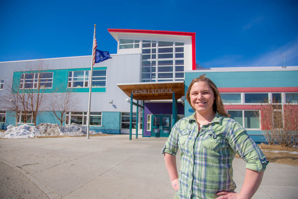 A teacher poses in front of Denali Elementary School