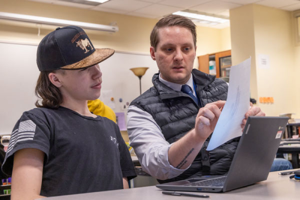 A UAF School of Education student teacher working with a student in a high school