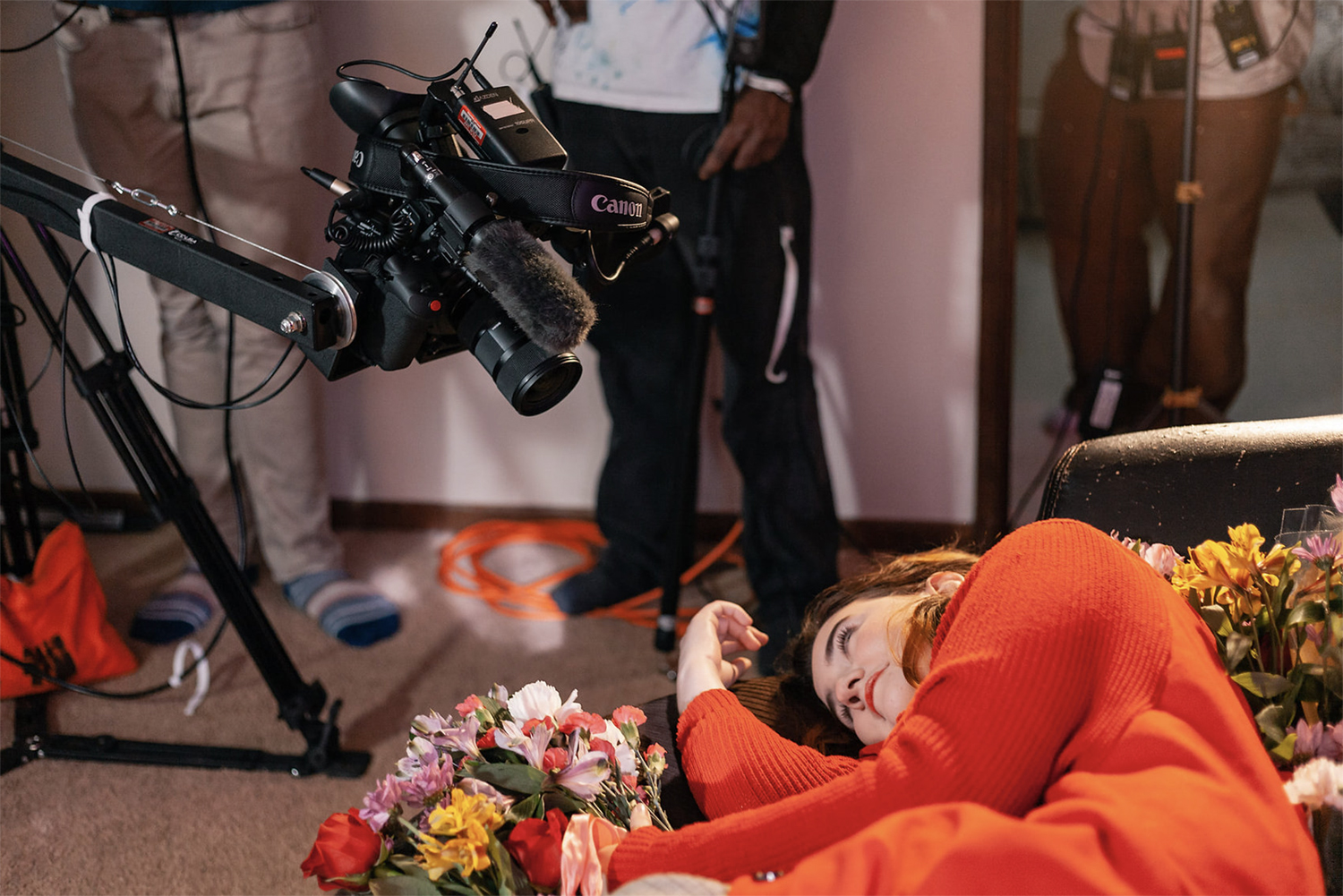 Behind the scenes photo from the shooting of Pink Violet where an actress lies surrounded by roses. Image by Maya Salganek