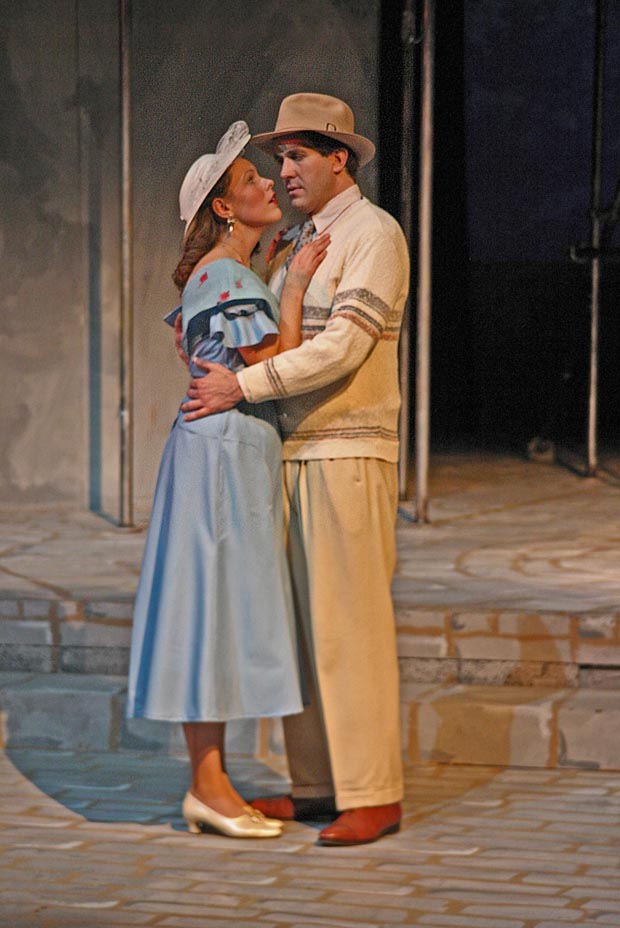 A man and woman in an embrace on stage.