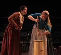 Actors on stage during the 2010 production of Vinegar Tom. One actress leans in to talk to another actress who is churning butter.| Photo courtesy of Stephan Golux