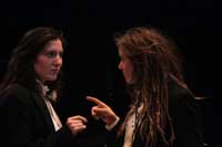 Actors on stage during the 2010 production of Vinegar Tom. Two actresses in suits point at each other in recognition and confusion| Photo courtesy of Stephan Golux
