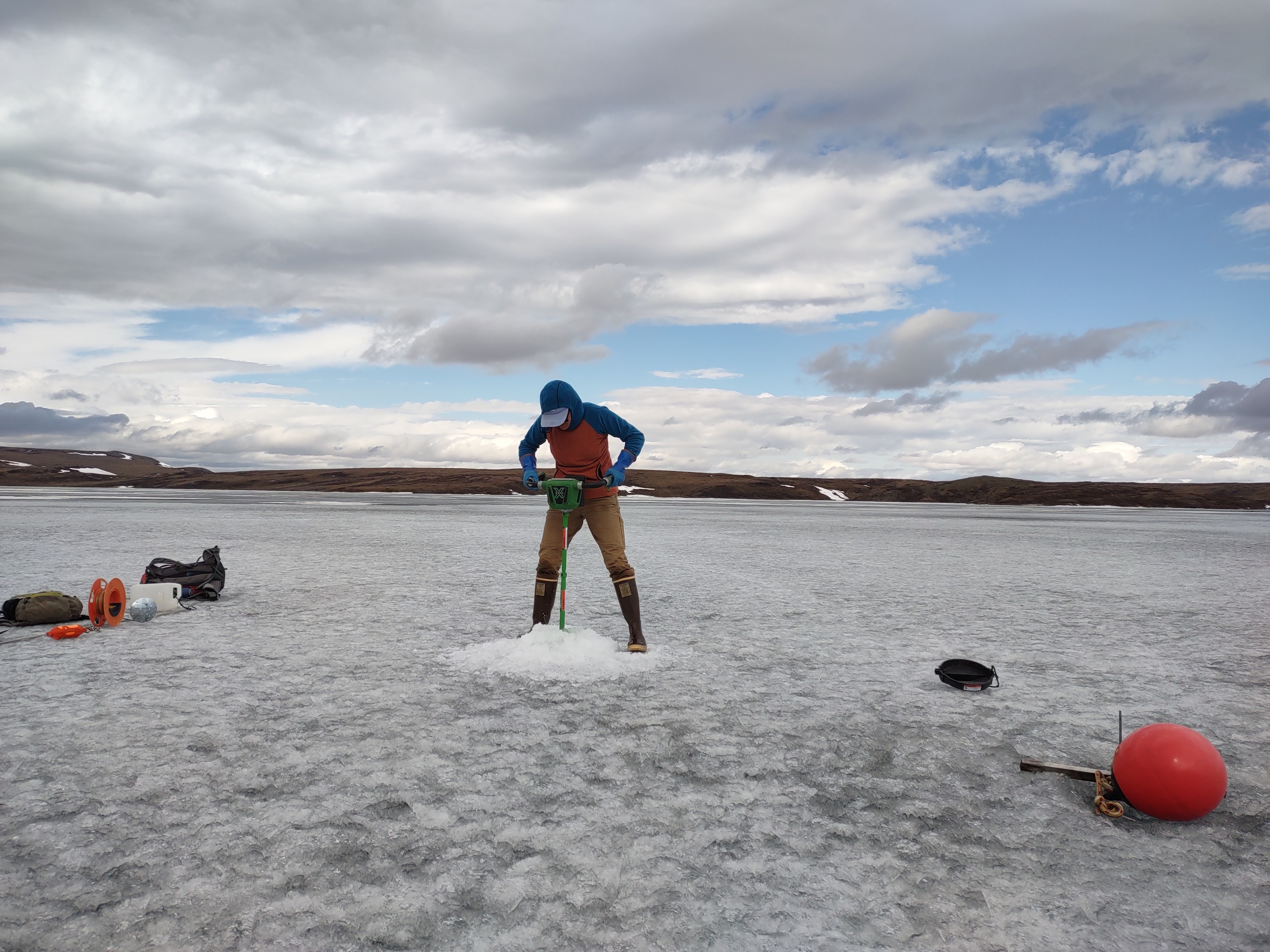 Photo by Amanda Young/Toolik Field Station
Toolik Field Station staff member Mayra Melendez Gonzalez drills into the ice on Toolik Lake to measure its thickness for long-term records in June 2022.