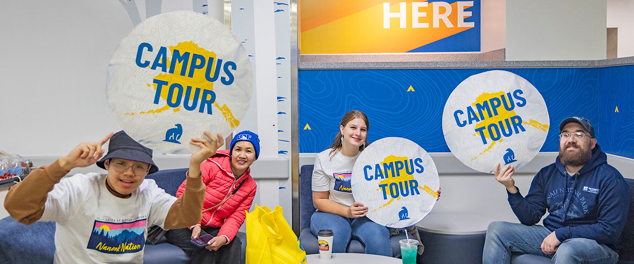 UAF student tour guides pose with their campus tour signs