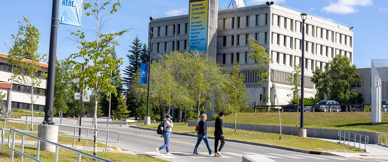 Students walk past centennial plaza with the Gruening Building in the background