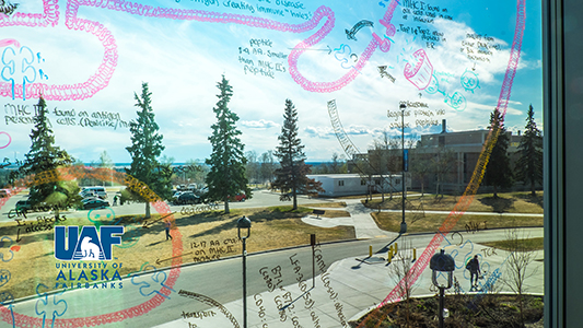 Academic notes written on a glass window in the Murie Building with the UAF logo in the lower left corner.