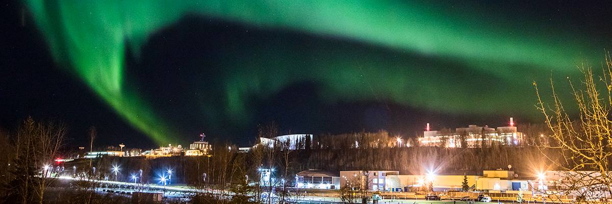 The Aurora Borealis is seen over the UAF campus on a dark winter night