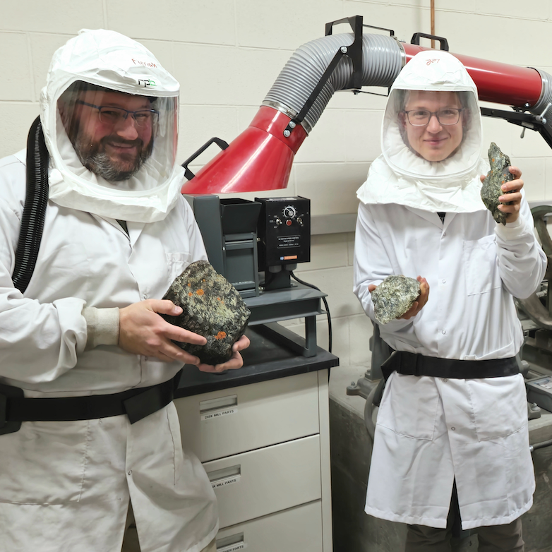 Lee and Florian hold samples while dressed in ppe