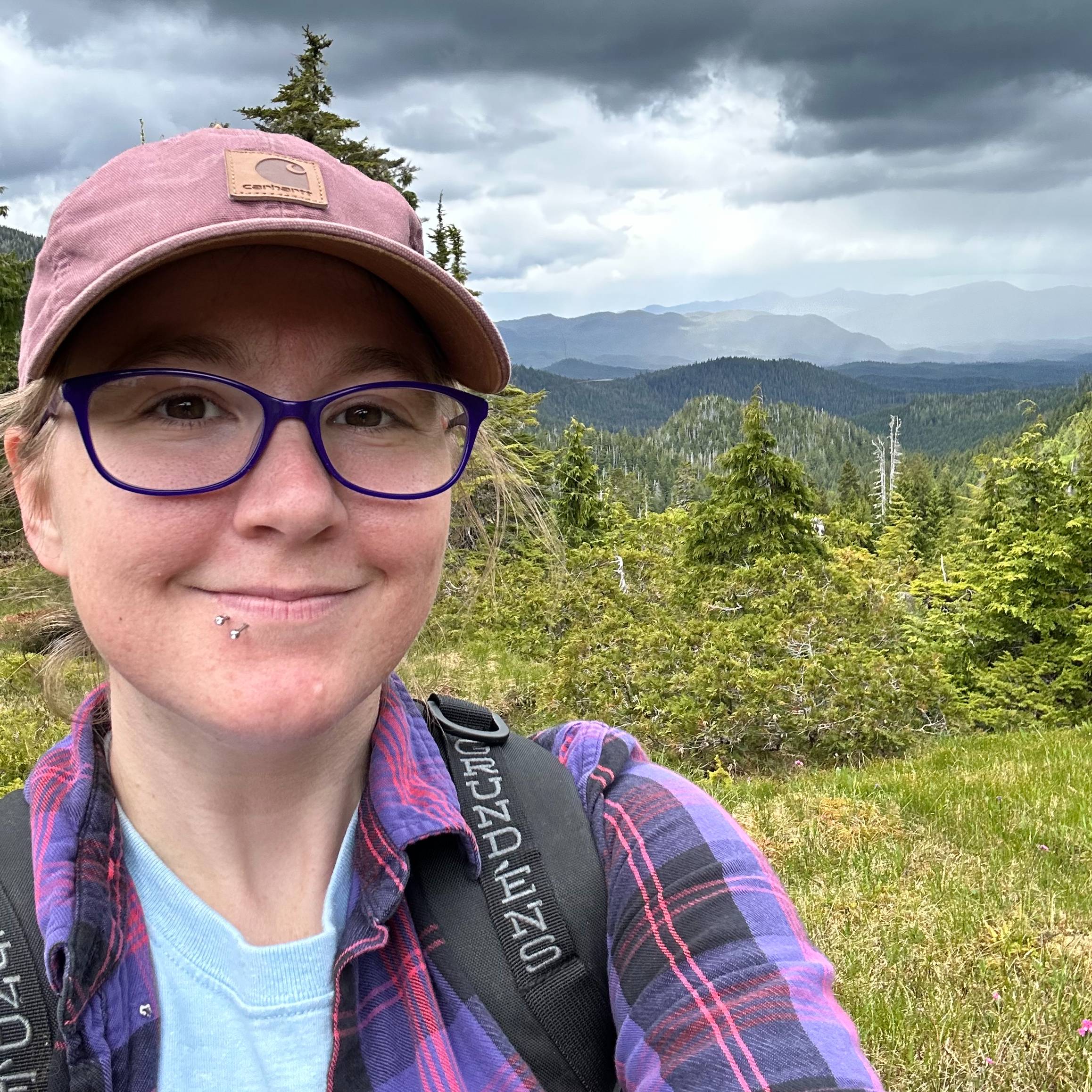 Bree Smith takes a selfie in front of greenery and a gray sky