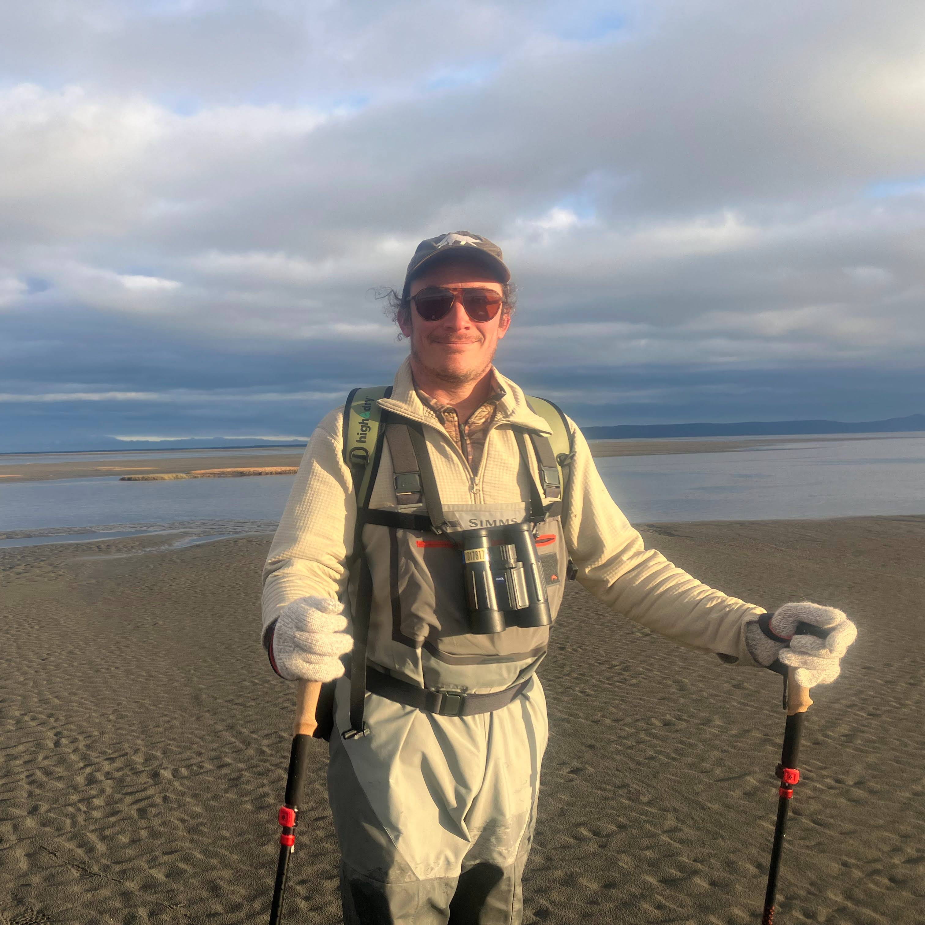 Danny Casner award photo on a beach holding hiking poles