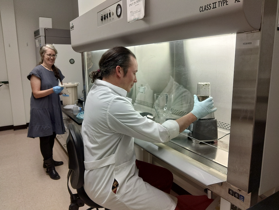 Danny and Dr. Wolf work in the lab under a fume hood