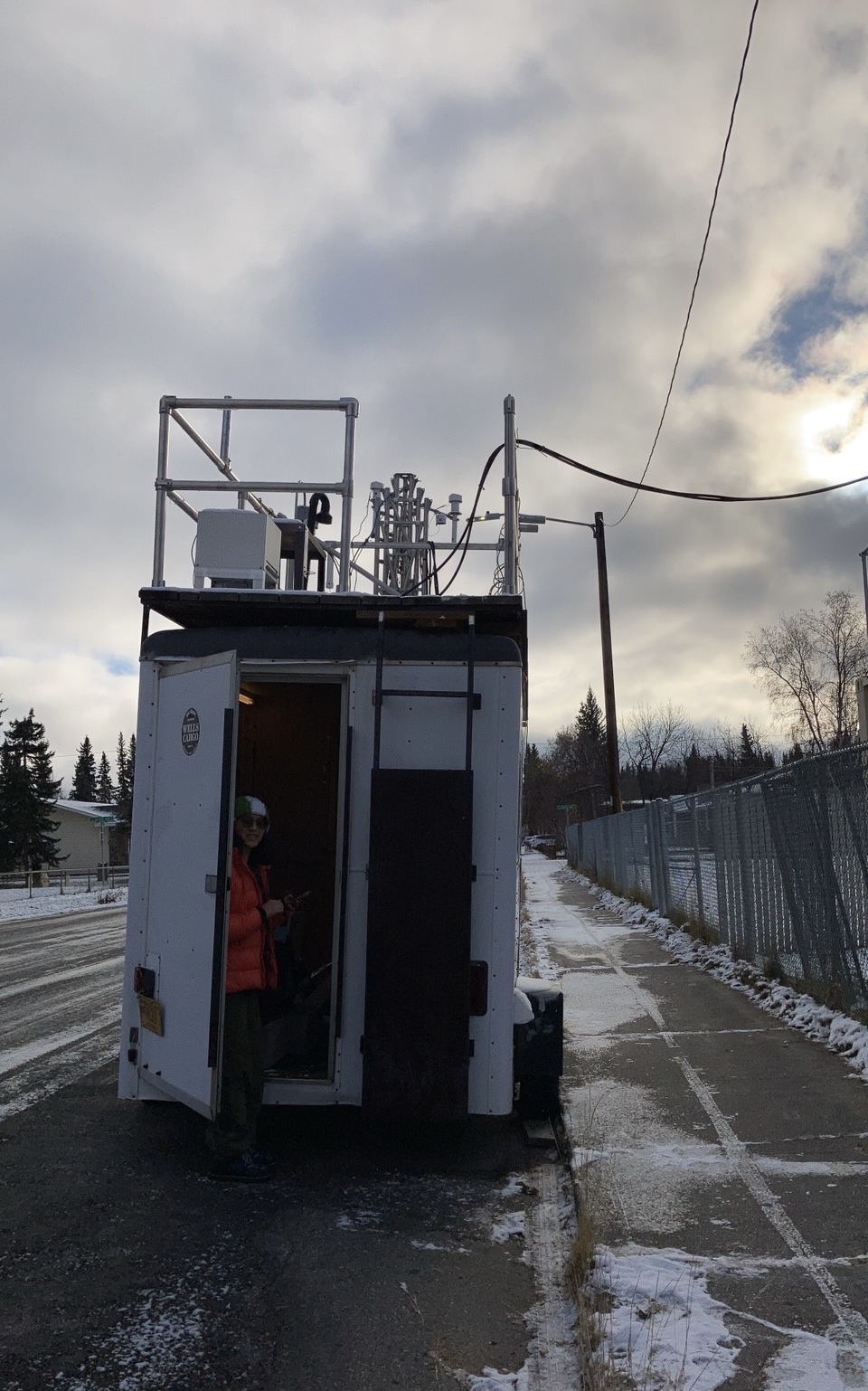 Anastasia next to the trailer tower's entry which is parked next to the Fairbanks A Street air quality monitoring site. Measurements collected from the trailer will be calibrated against respective data from the monitoring site.