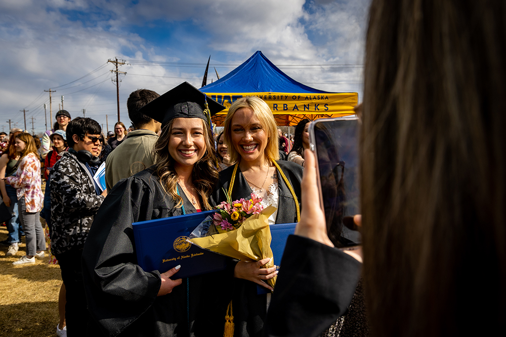 Emily Pilkinton(left) and Kennedy Atlee(right) take a photo together outside of the Carlson Center after graduating in UAF's 2023 Commencement Ceremony, 5/6/23. (UAF photo by Leif Van Cise)