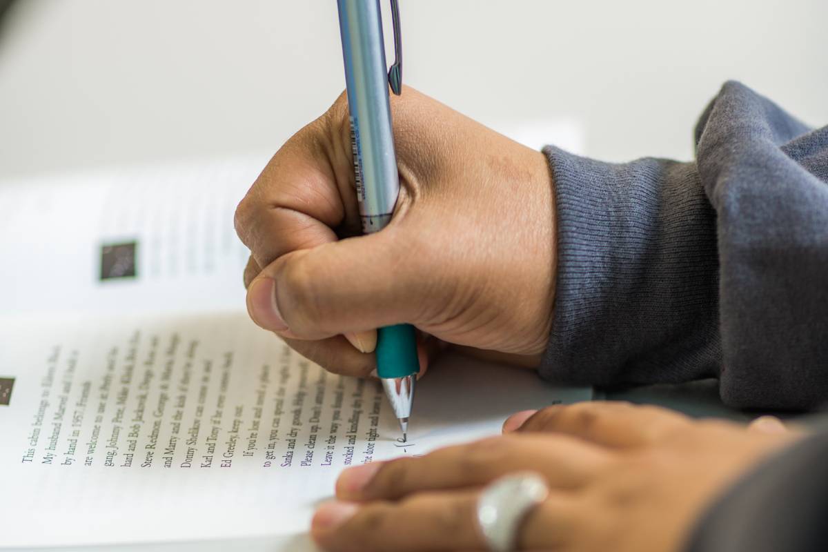 A student jots down a note in her English book during class.